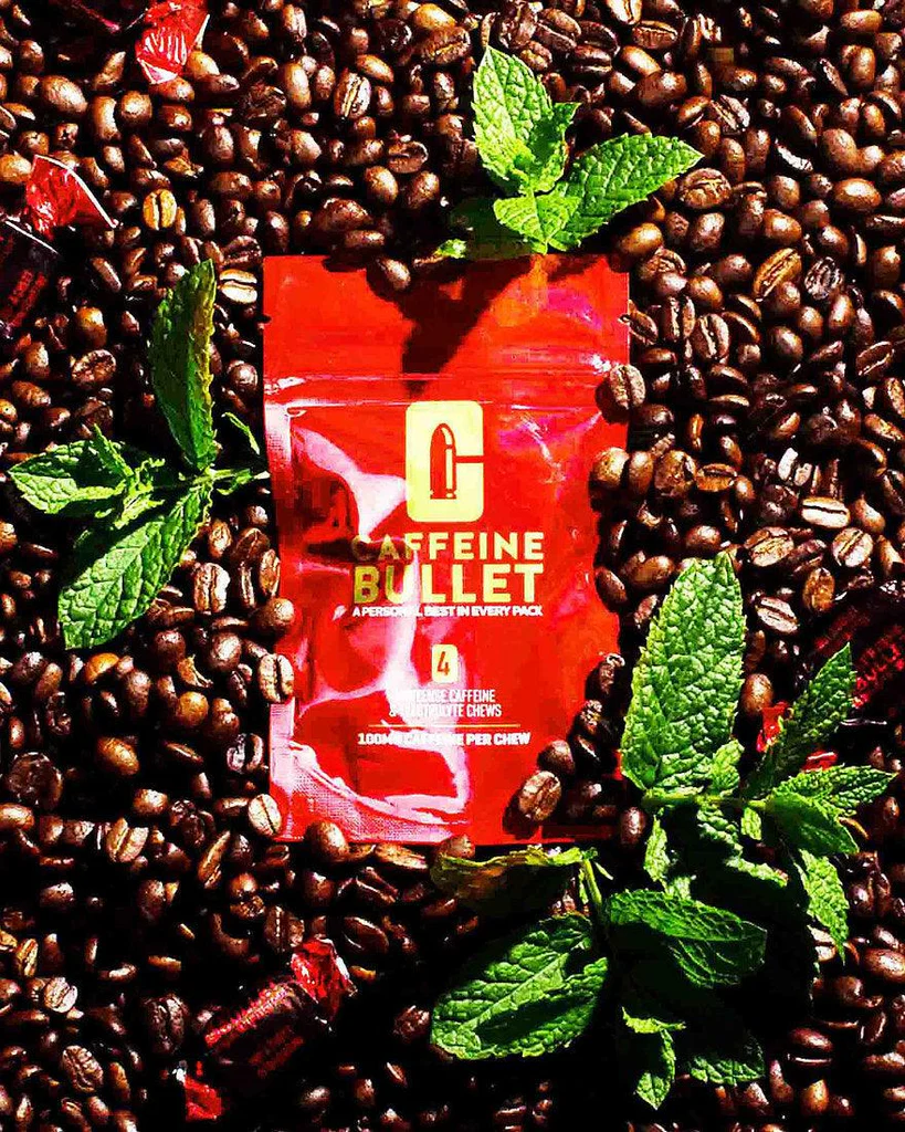 Caffeine Bullet Mintense 100mg and ChocoLIT 85mg energy chew packaging side-by-side on a desk, showing caffeine content and electrolytes.